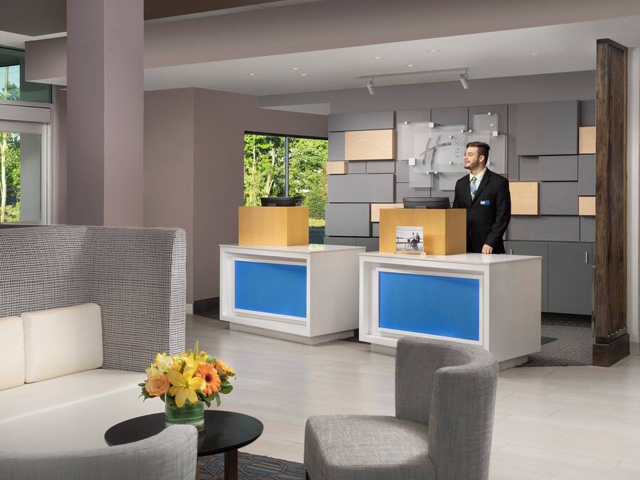 Et hotellets receptionområde med receptionsdisk, siddepladser og et køleskab fyldt med drikkevarer.