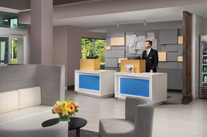 A hotel reception area with a reception desk, seating area, and a refrigerator stocked with beverages.