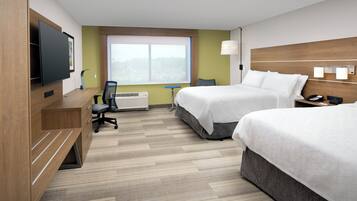 Une chambre d’hôtel avec deux lits, un bureau, une chaise, une télévision et une fenêtre.