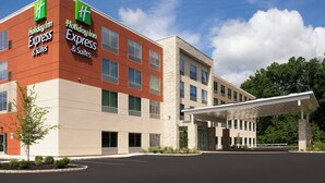 A Holiday Inn Express & Suites hotel with a modern design, featuring a mix of brick and stone facades, large windows, and a covered entrance. - Holiday Inn Express and Suites North Brunswick by IHG (North Brunswick)