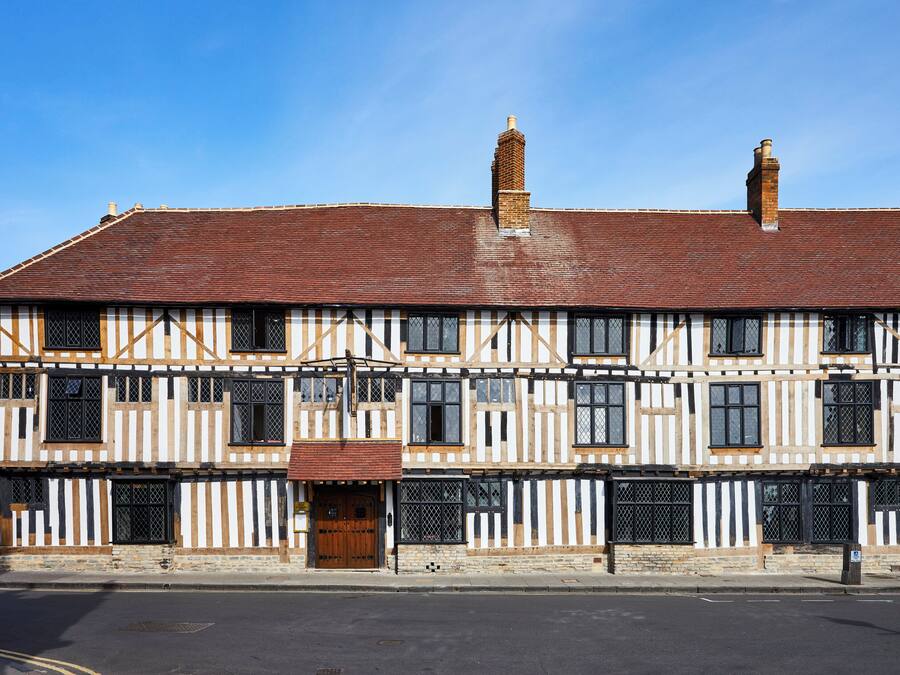 A traditional half-timbered building with a symmetrical facade, multiple windows, and a central entrance.