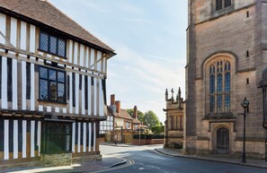 A street with traditional half-timbered buildings and a stone church. - Hotel Indigo Stratford Upon Avon by IHG (Stratford-upon-Avon)