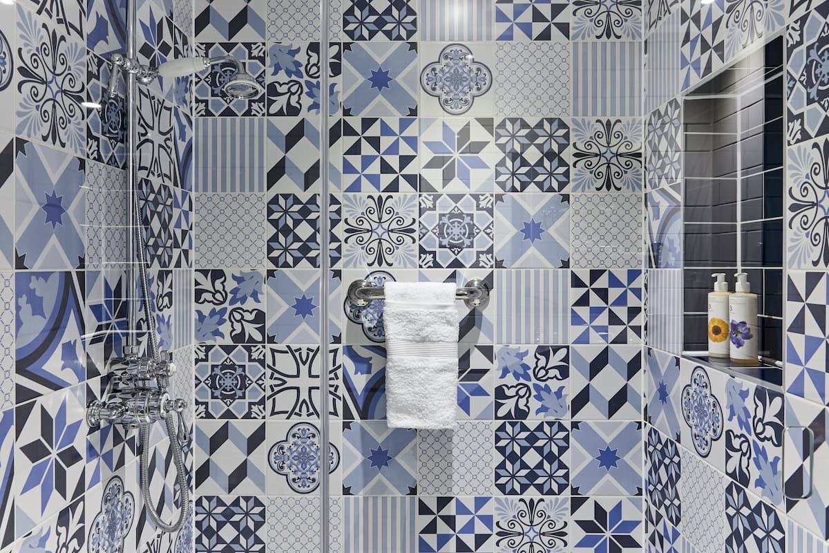 A bathroom with a variety of blue and white geometric tile patterns.