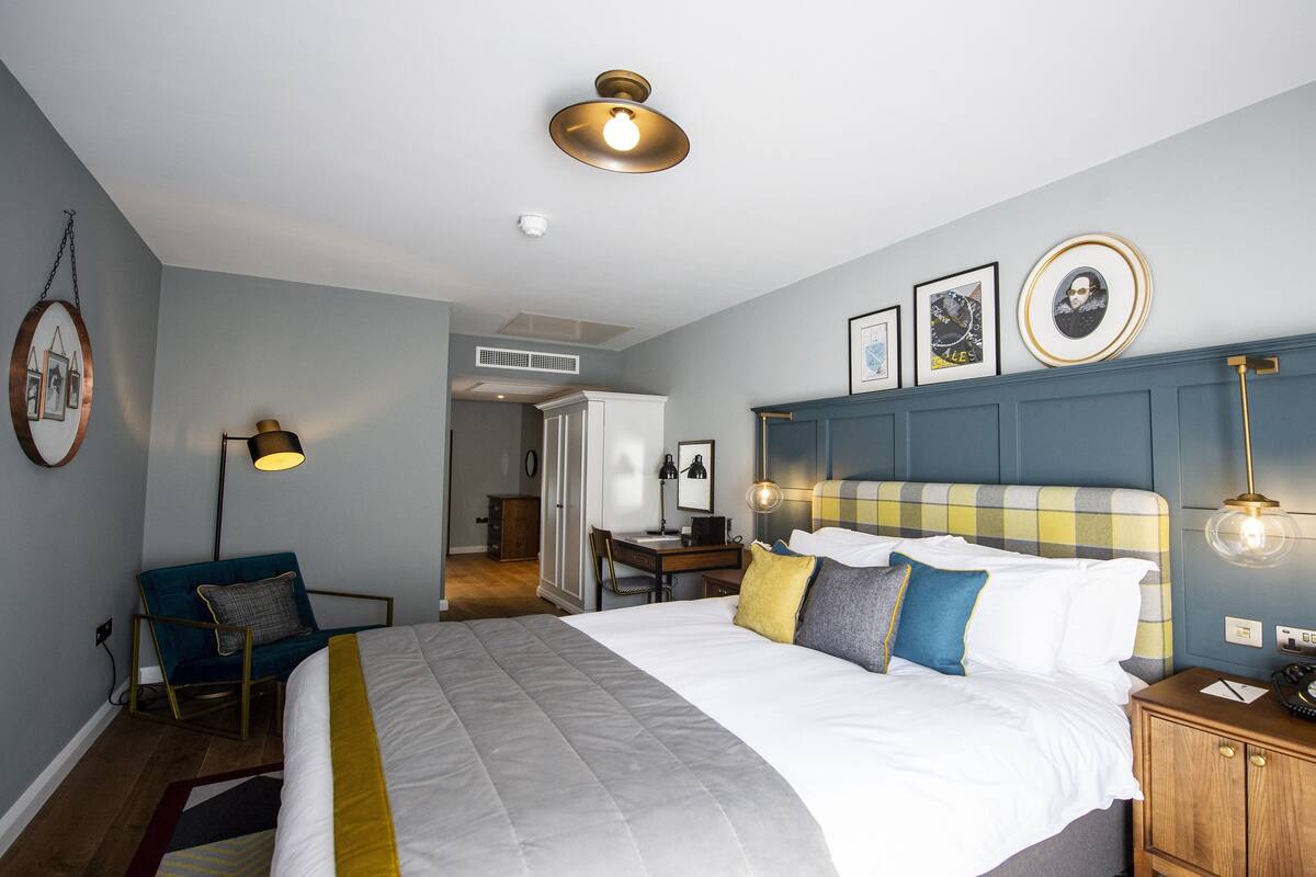 A hotel room with a bed, bedside table, lamp, and a wardrobe.