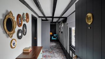 A hallway with a wooden desk, a blue chair, and a door with a number plate.