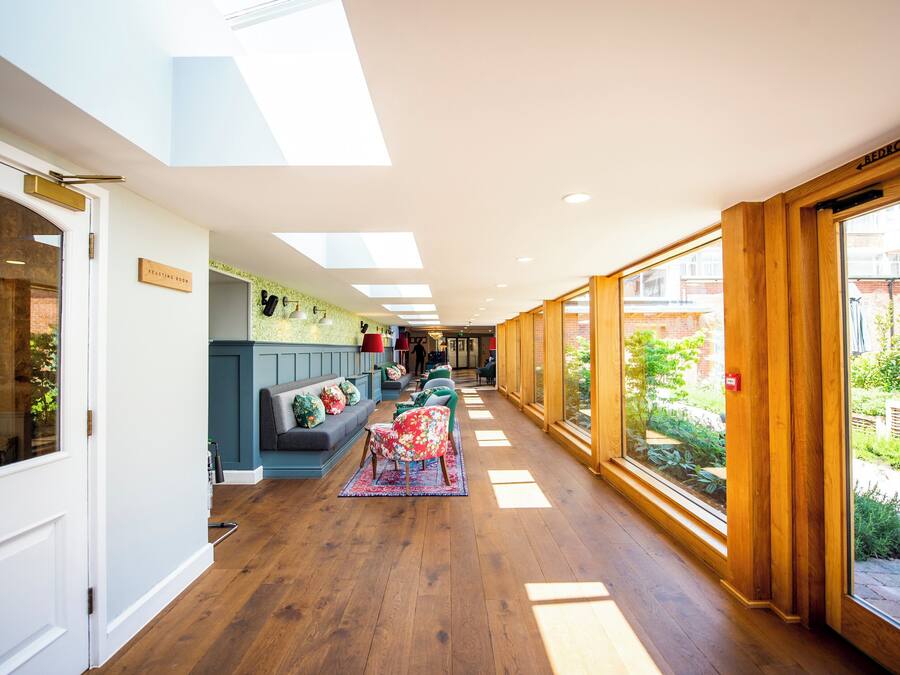 A corridor with a wooden floor, a blue sofa with floral cushions, and a red chair.