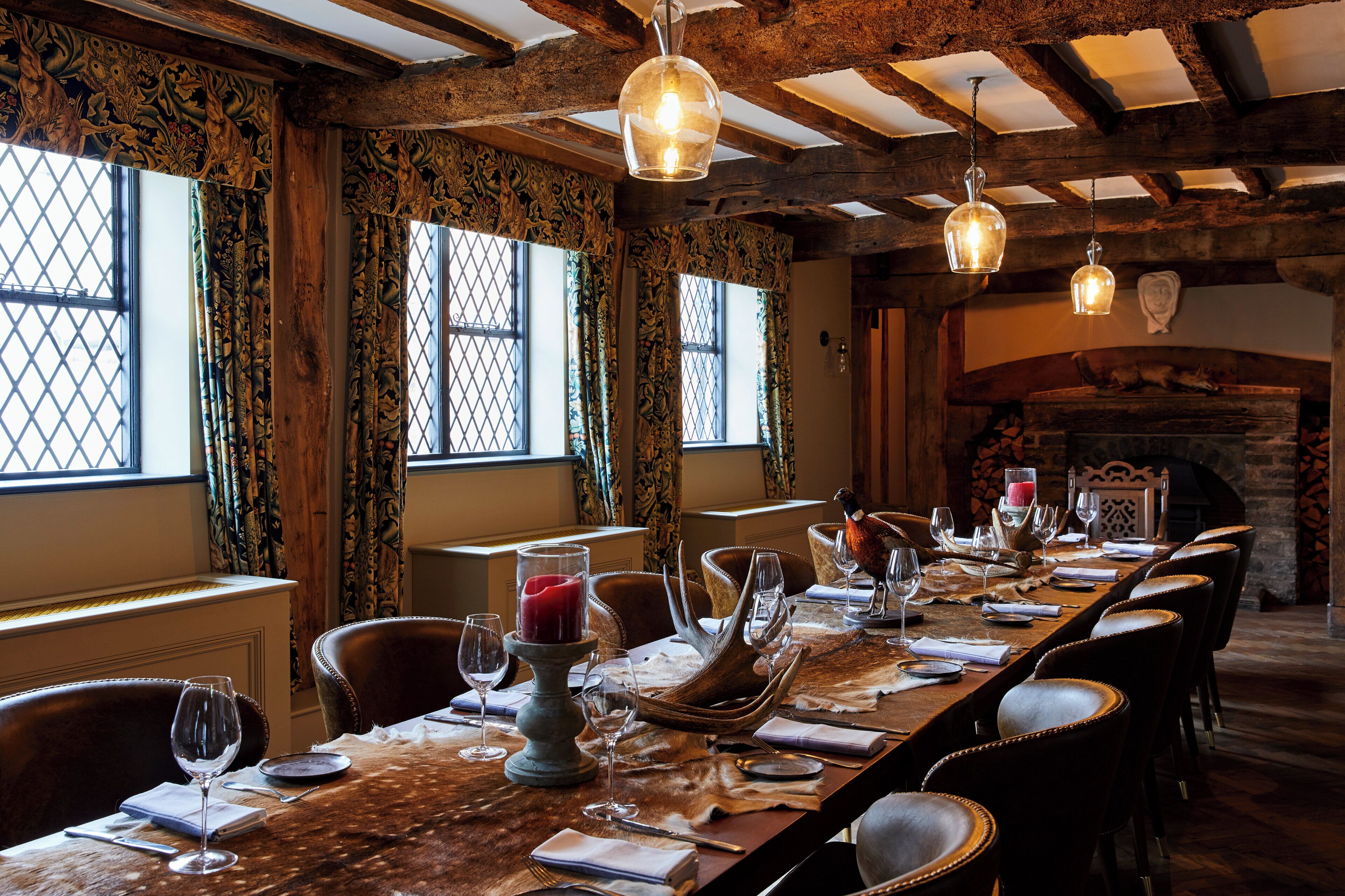 A long dining table set for a meal with chairs, wine glasses, and a candle centerpiece.