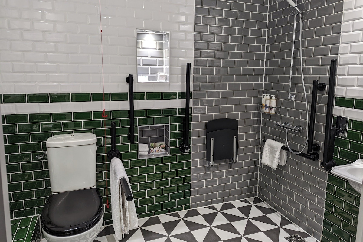 Ein Badezimmer mit Toilette in Weiß, einem schwarzen Waschbecken und einer Duschkabine.