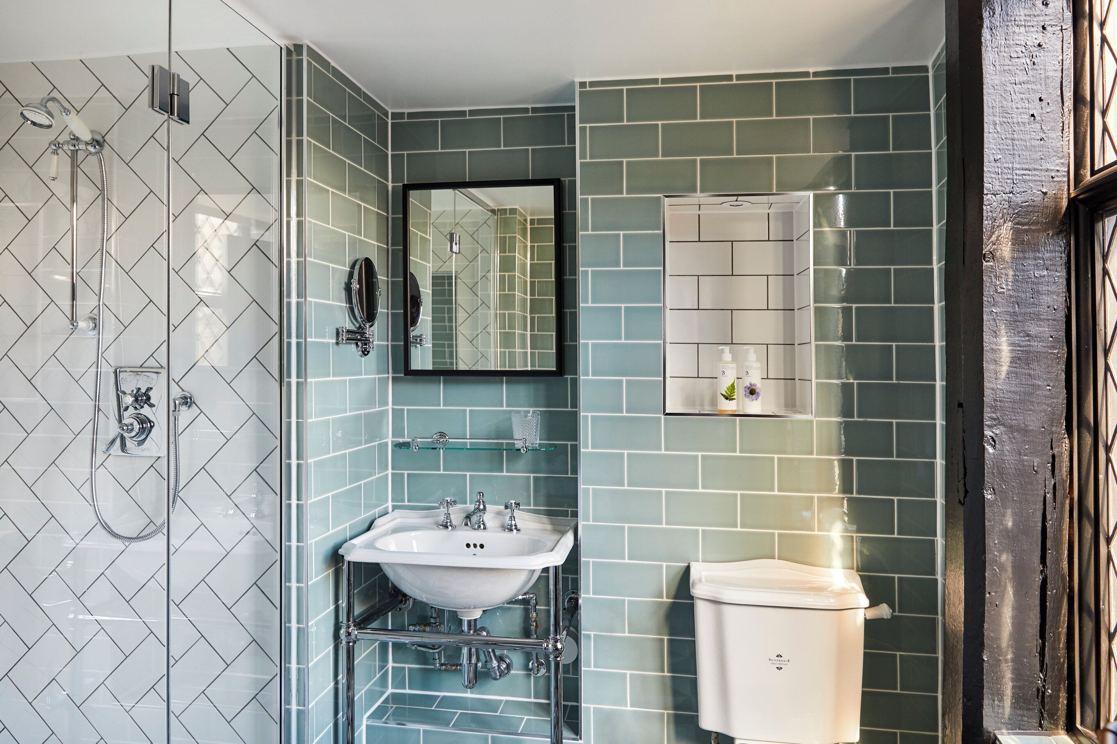 A bathroom with a glass shower enclosure, a sink with a mirror, and a toilet.