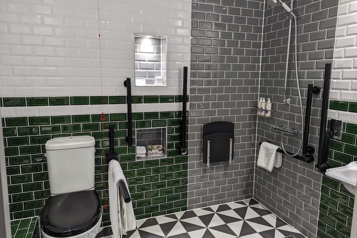 A bathroom with a white toilet, a black sink, and a shower area.