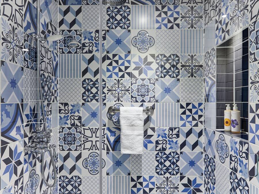 A bathroom with a variety of geometric tile patterns and a visible shower area.