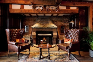 A cozy lounge area with leather armchairs, a small round table, and a brick fireplace. - Hotel Indigo Stratford Upon Avon by IHG (Stratford-upon-Avon)