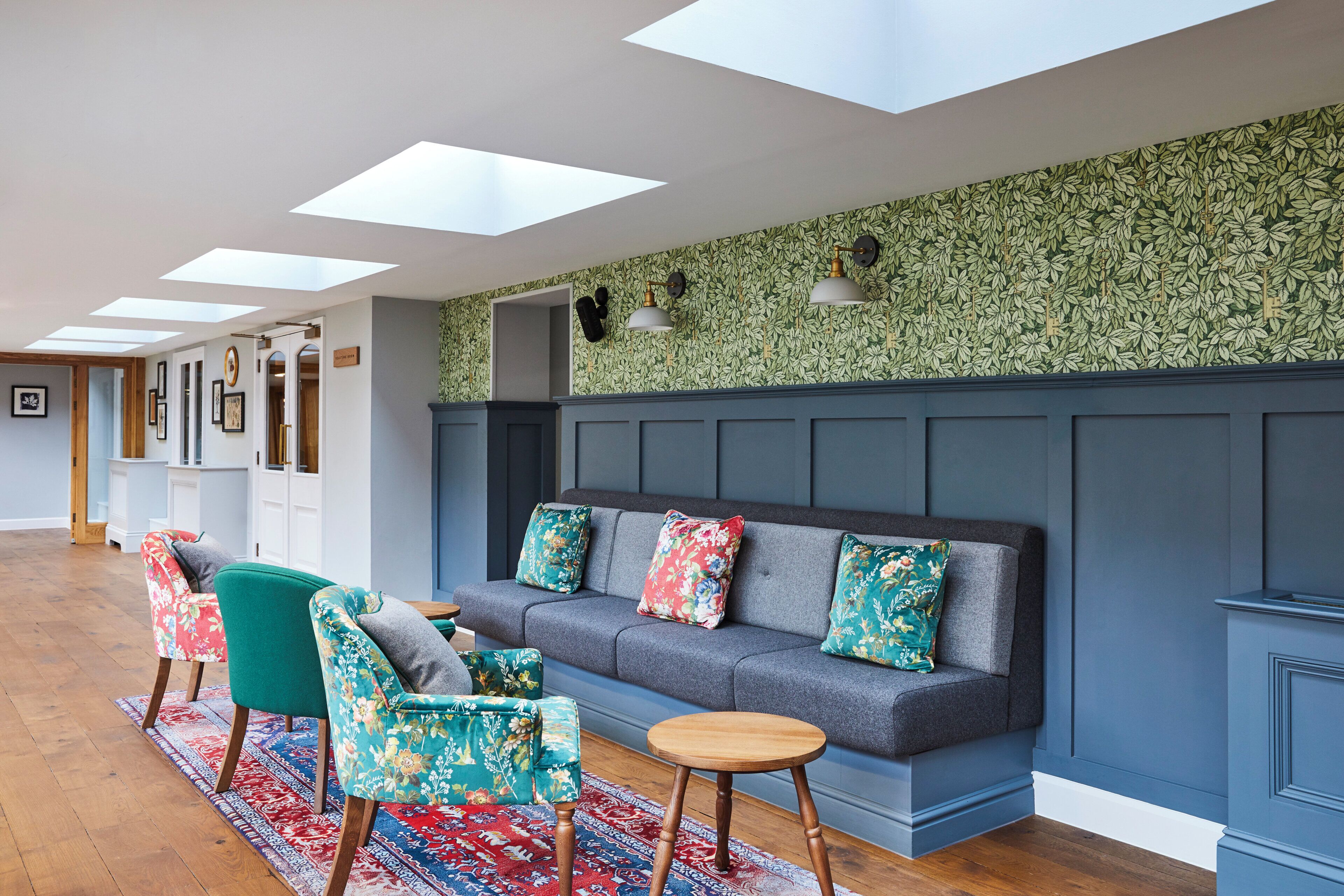 A modern lounge area with a sofa, chairs, and a patterned wall.