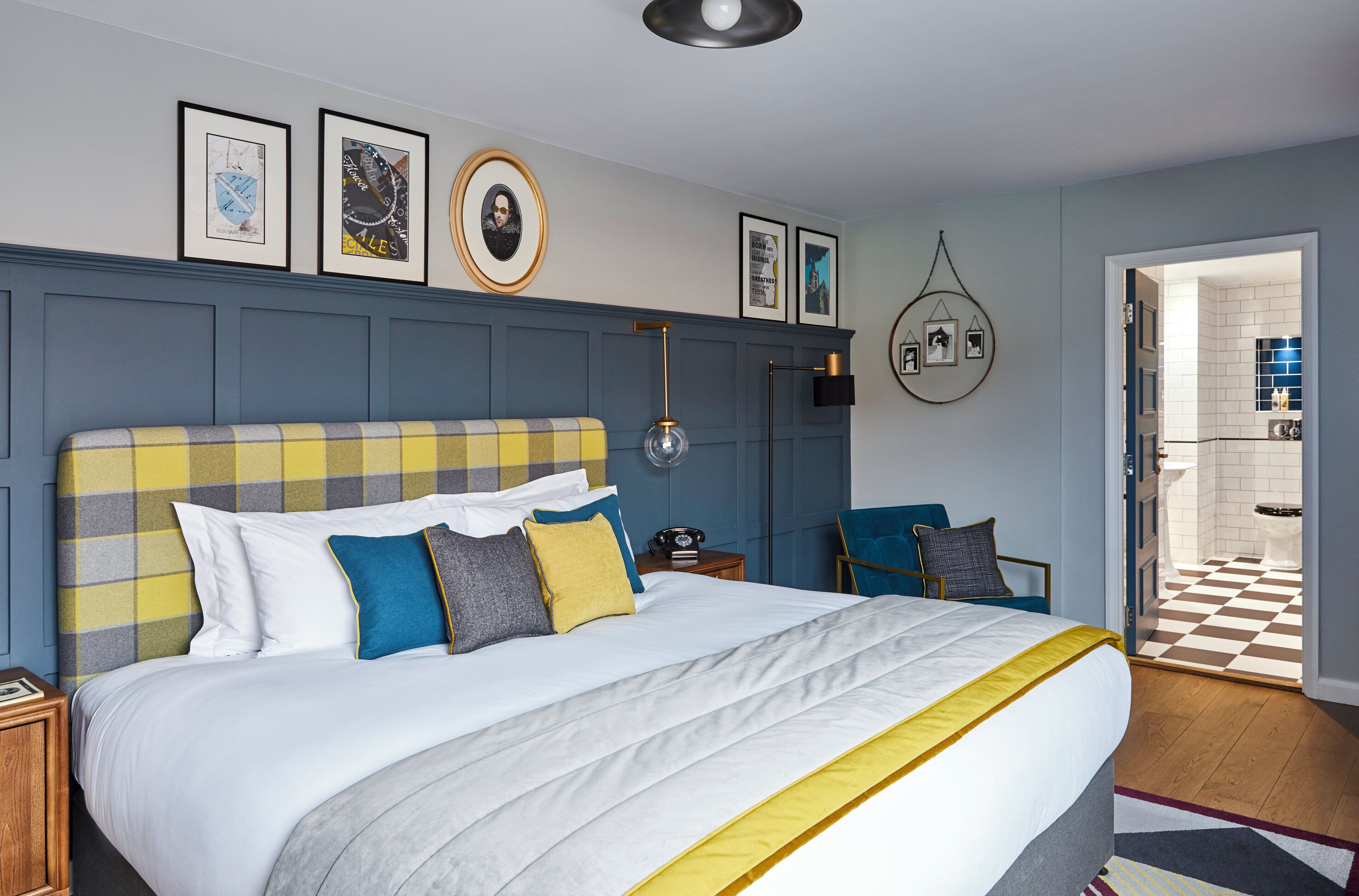A hotel room with a large bed, a bedside table, a chair, and a view of the bathroom.