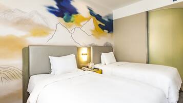 A hotel room with two beds, a nightstand with a phone and a lamp, and a wall with a mountain landscape mural.