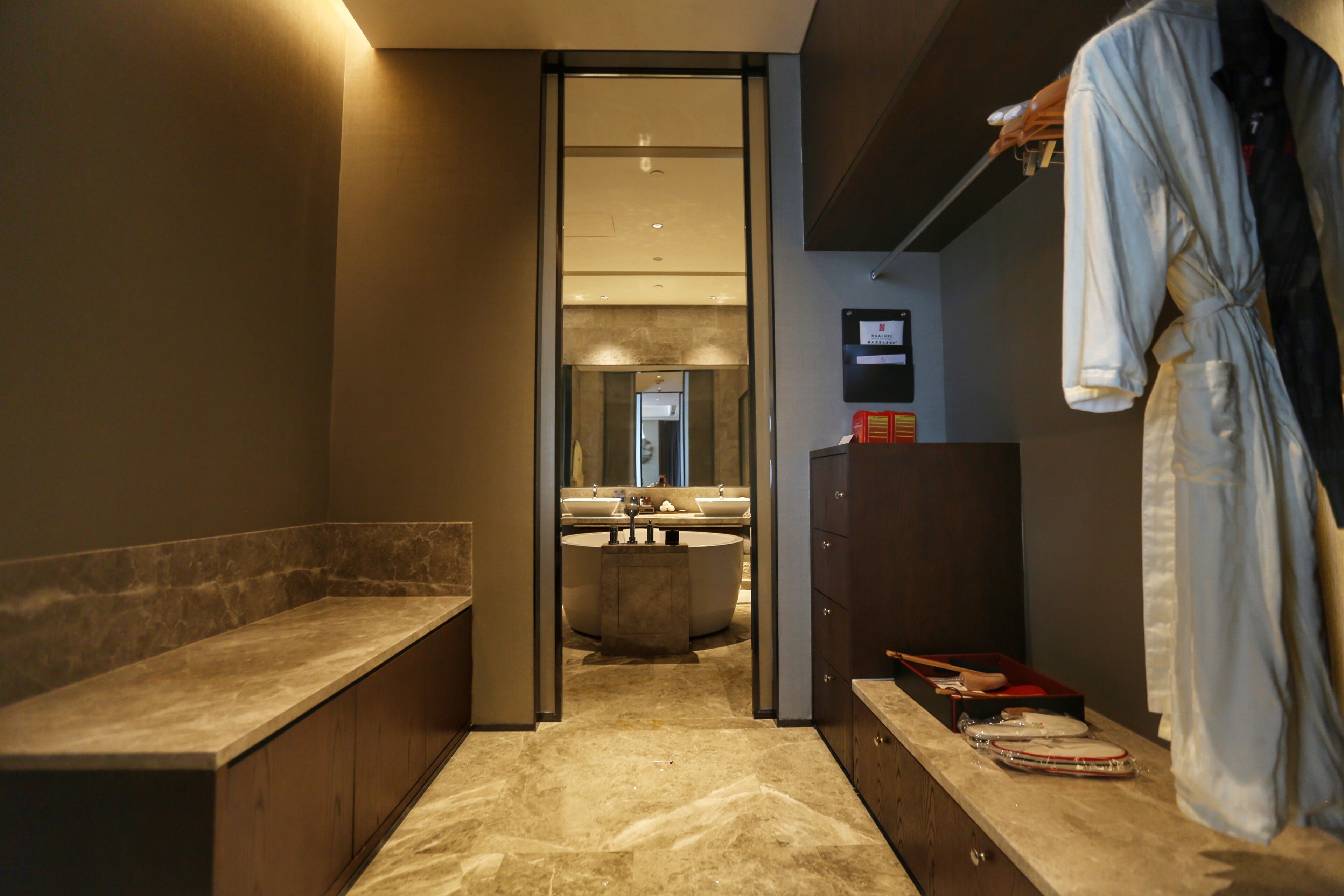 A modern bathroom with a large bathtub, a vanity with a mirror, and a robe hanging on a rack.