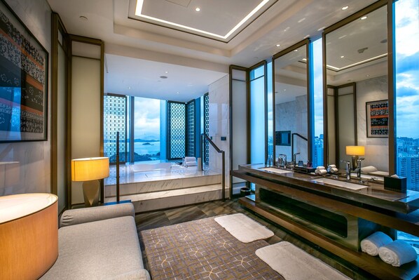 A modern bathroom with a large mirror, a bathtub, and a view of the cityscape. - HUALUXE Xiamen Haicang Harbour View by IHG (Xiamen)