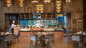 Un restaurante con barra central, diversas opciones de asientos y un chef preparando comida.