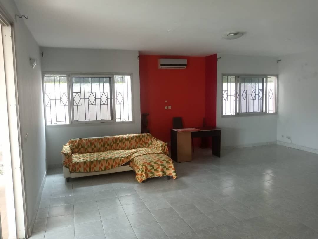 Una habitación amplia con sofá, una mesita y una pared decorada en rojo.