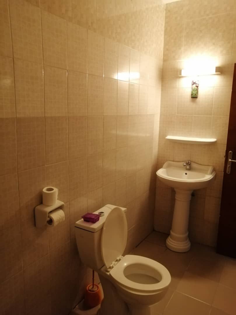 A bathroom with a toilet, sink, and a wall-mounted toilet paper holder.