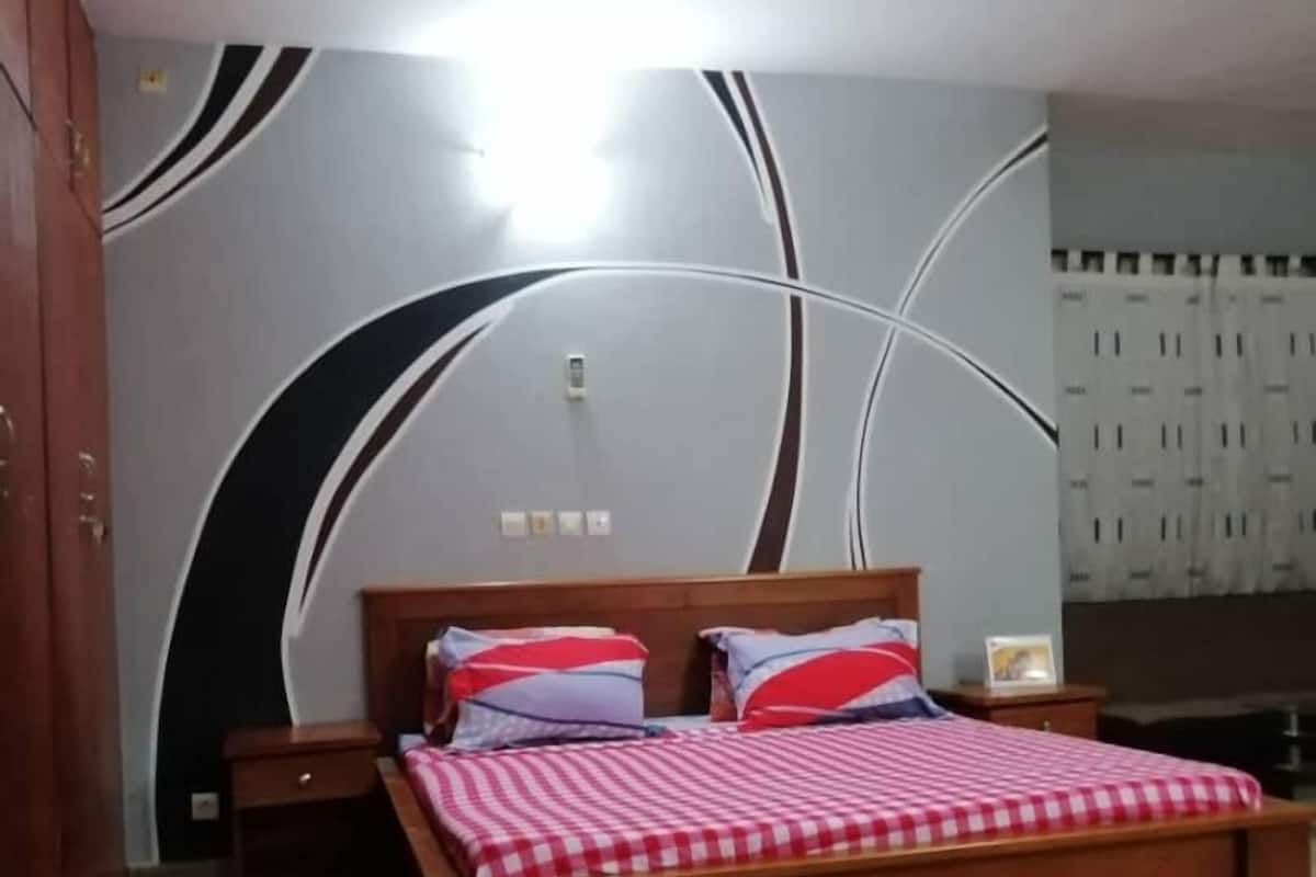 A bedroom with a wooden bed, a nightstand, a wardrobe, and a wall with a modern design.