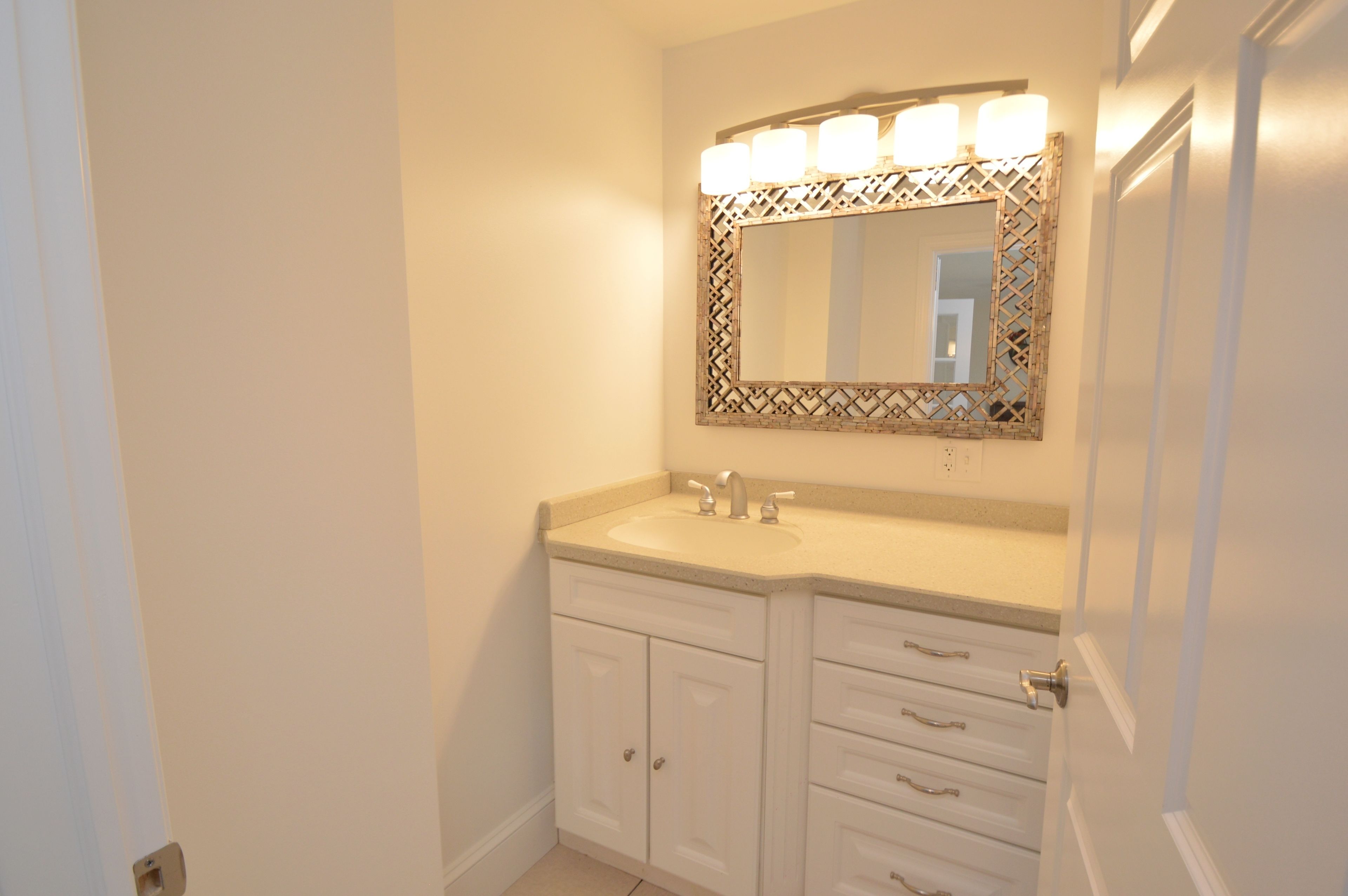 Une salle de bain avec un meuble-lavabo double, un miroir avec éclairage intégré et une porte.