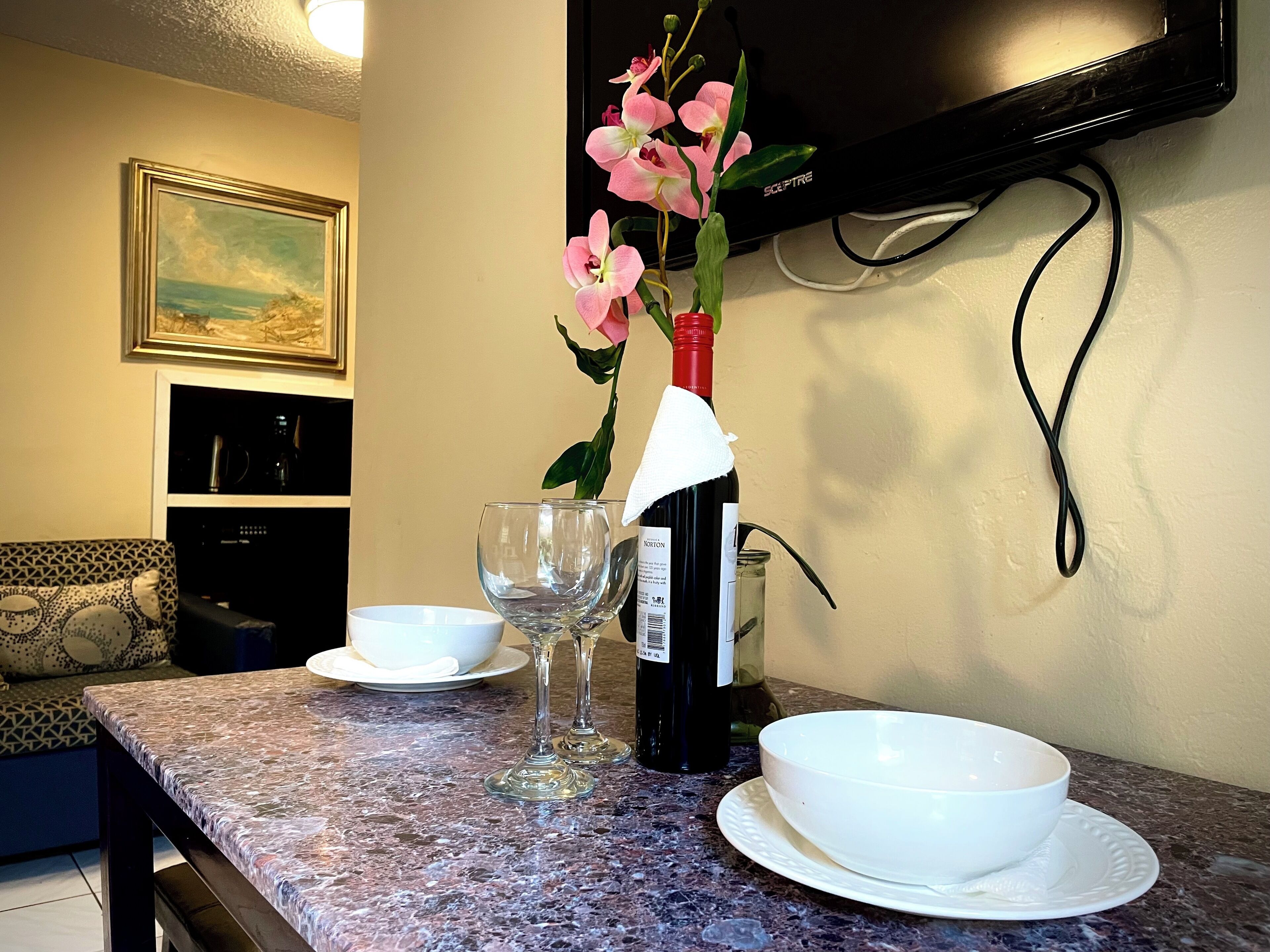 A dining table with a wine bottle, a glass, and a bowl.