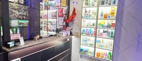 Un área de recepción con un mostrador de madera, una vitrina de vidrio con varios productos y una pared con múltiples letreros y certificados.