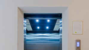 Un ascensore con un pannello di controllo digitale e una porta in vetro.