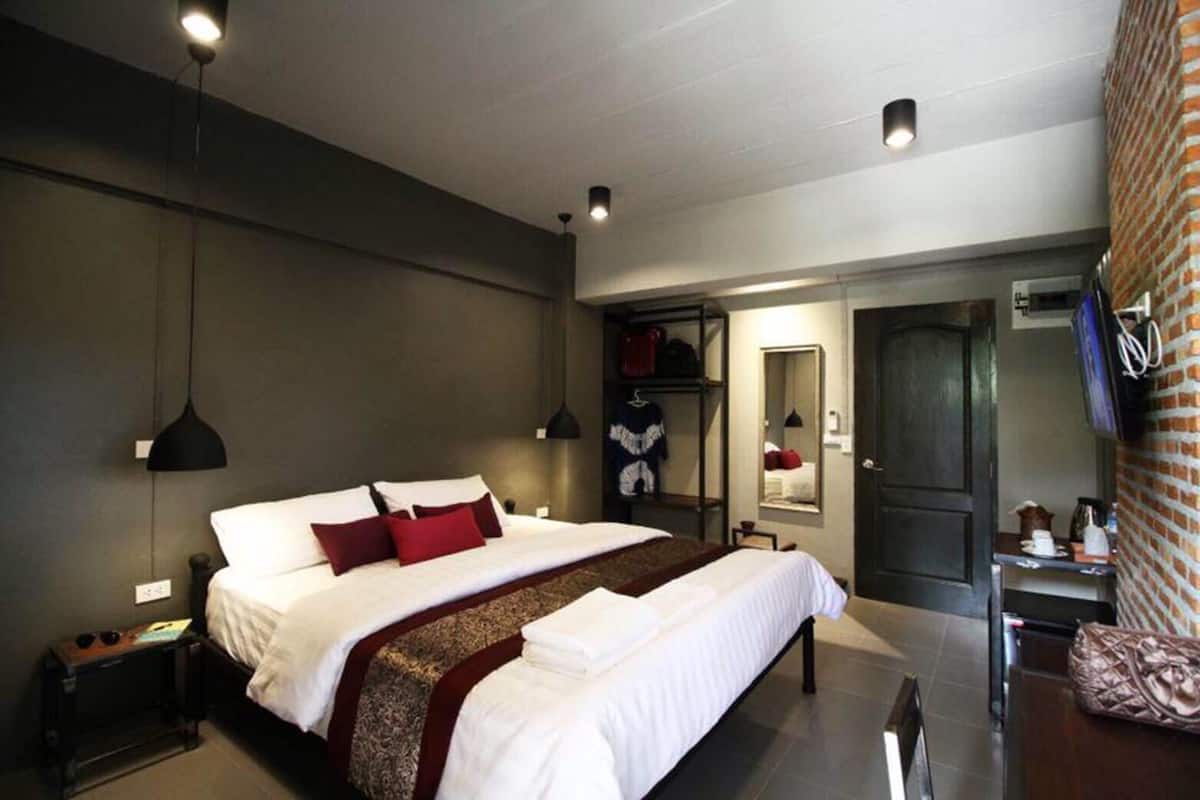 A modern hotel room with a large bed, bedside tables, a wardrobe, and a mirror.