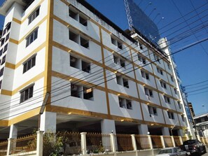 Un hotel de varios pisos con fachada blanca y detalles amarillos, que presenta una cuadrícula de ventanas y balcones.