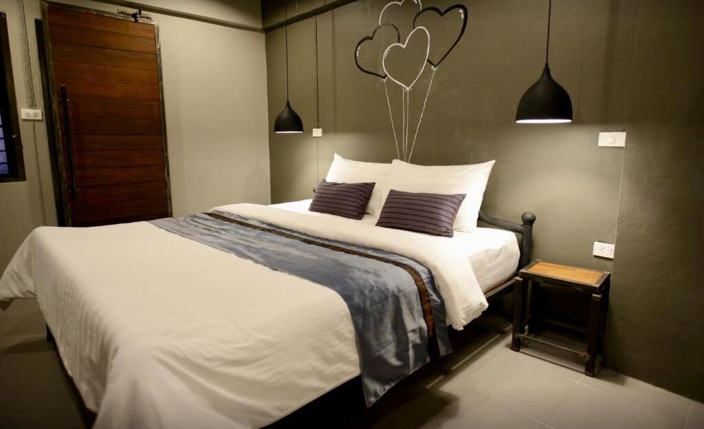 A neatly made bed with a white and blue bedspread, two pillows, and a bedside table with a lamp.