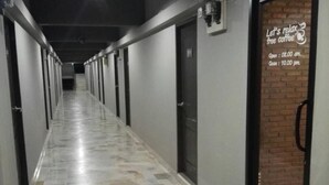 Un pasillo con suelo de baldosas, puertas a ambos lados y un cartel en la pared derecha que anuncia café gratis.
