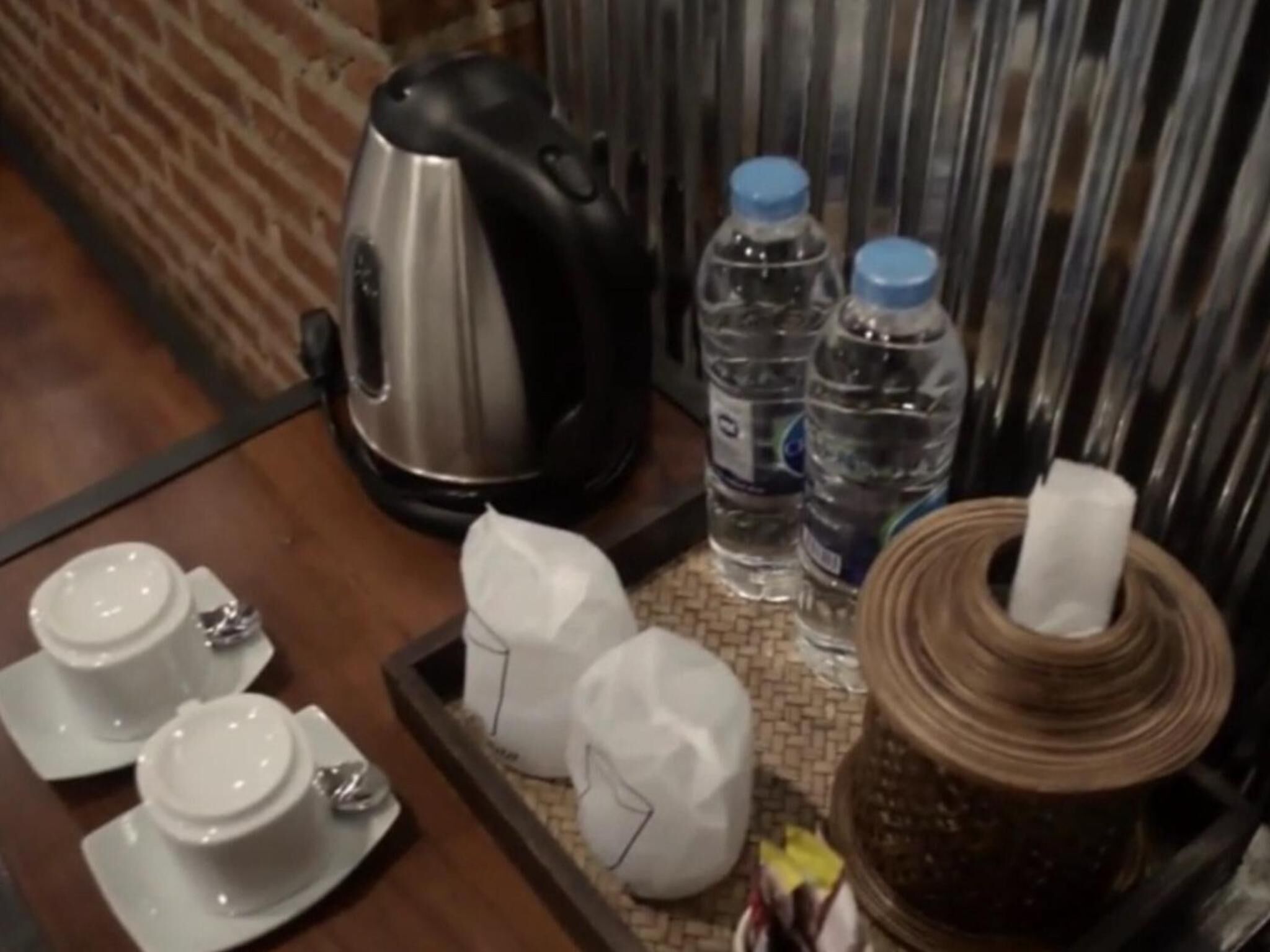 A tray with a kettle, water bottles, a tissue roll, and tea sets.