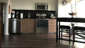 Une cuisine moderne dotée d’appareils électroménagers en acier inoxydable, de meubles en bois et d’un coin repas avec une table et des chaises.
