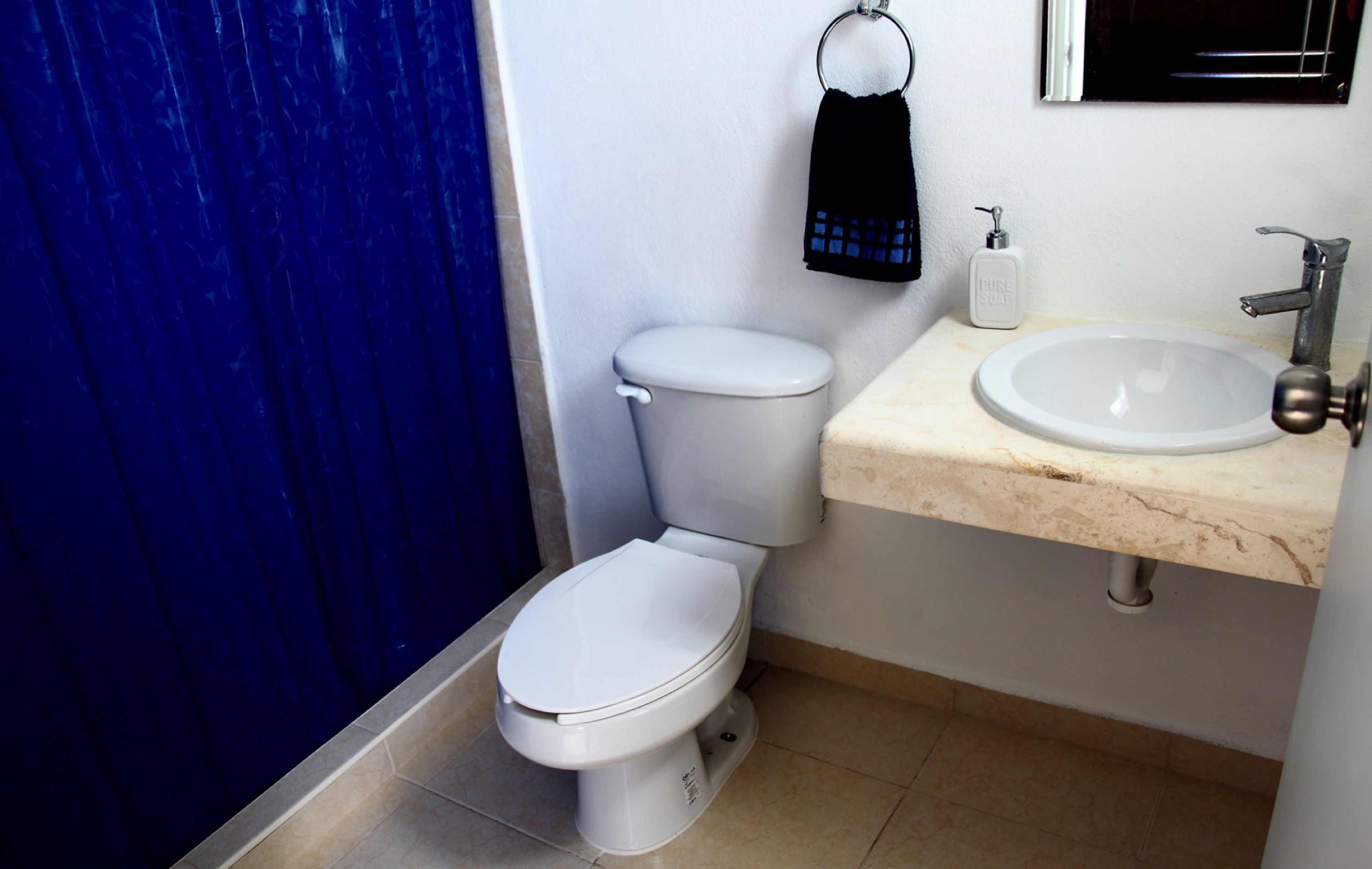 A small bathroom with a toilet, sink, and blue shower curtain.