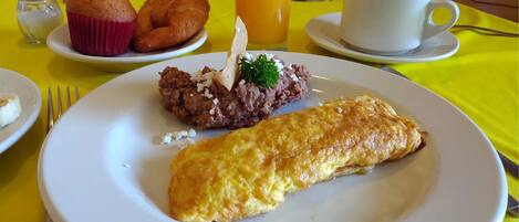 A breakfast setting with a plate of food, a glass of orange juice, and a cup of coffee on a yellow tablecloth.