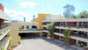 A multi-story parking garage with a pool area, surrounded by buildings with balconies and potted plants.