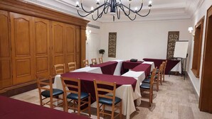 A conference room with wooden paneling, a chandelier, and tables set for meetings.