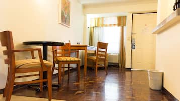 Une pièce meublée en bois, comprenant une table et des chaises, une poubelle et une porte avec une pancarte.