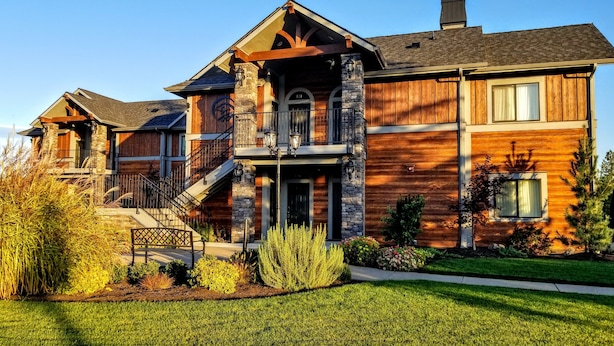 A large, multi-story house with a prominent stone facade, a wooden deck, and a well-maintained lawn. - Resort at Eagle Point (Eagle Point)