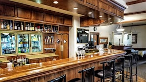 A bar area with wooden cabinets, a bar counter, and multiple stools. - Resort at Eagle Point (Eagle Point)
