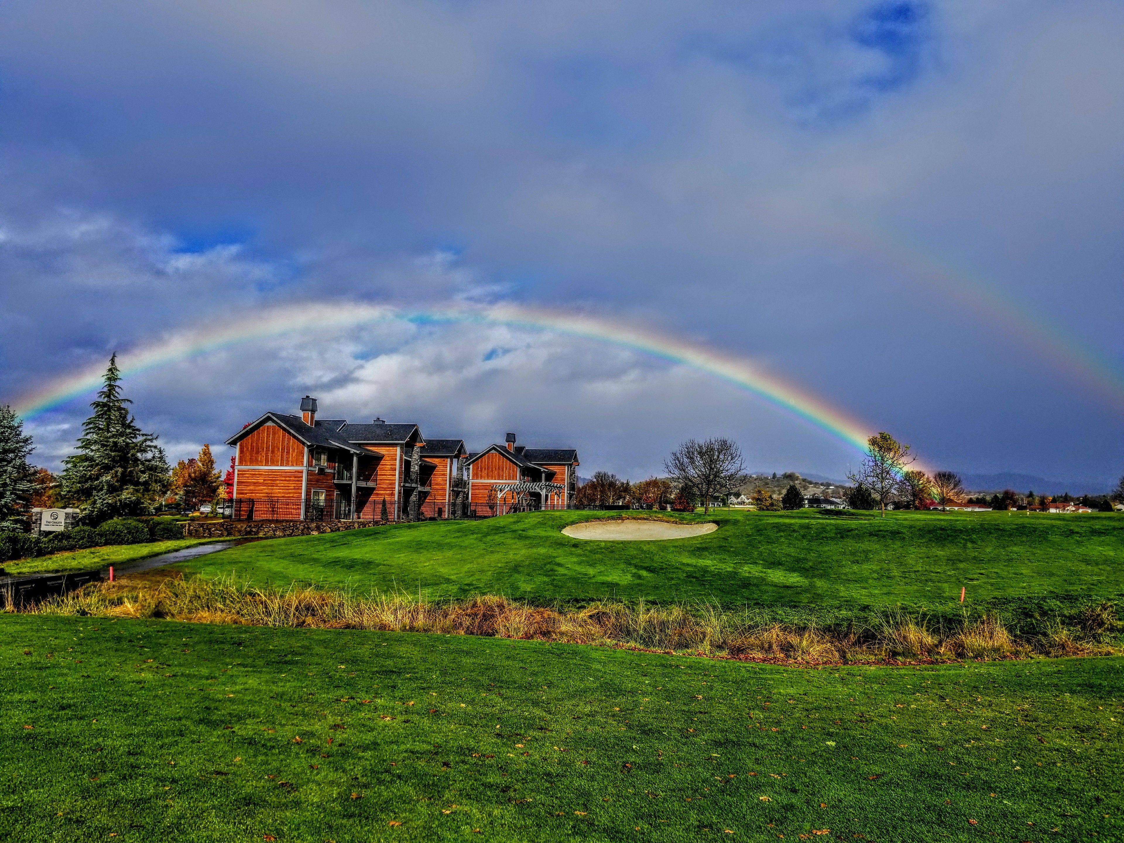 A large house with a well-maintained lawn and a golf course in the background.