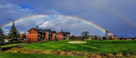 A large house with a well-maintained lawn and a golf course in the background.