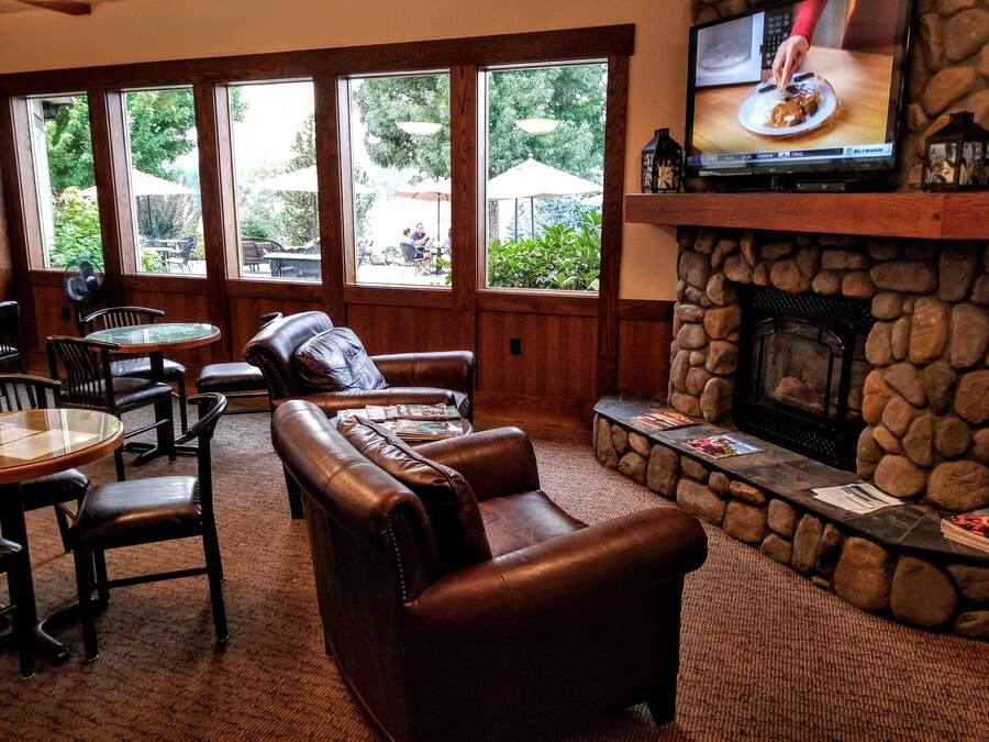 A cozy lounge area with leather sofas, a stone fireplace, and a TV mounted above it.