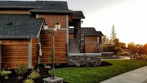 A modern house with a stone facade, wooden paneling, and a well-maintained lawn. - Resort at Eagle Point (Eagle Point)