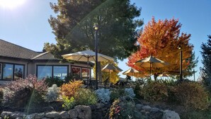 A patio area with outdoor seating and umbrellas, surrounded by a stone wall and various plants. - Resort at Eagle Point (Eagle Point)