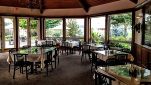 A restaurant with multiple tables and chairs, large windows offering outdoor views, and a chandelier. - Resort at Eagle Point (Eagle Point)