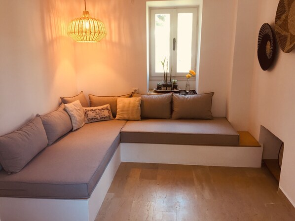 A modern living room with a sectional sofa, a hanging light fixture, and a window with a view.