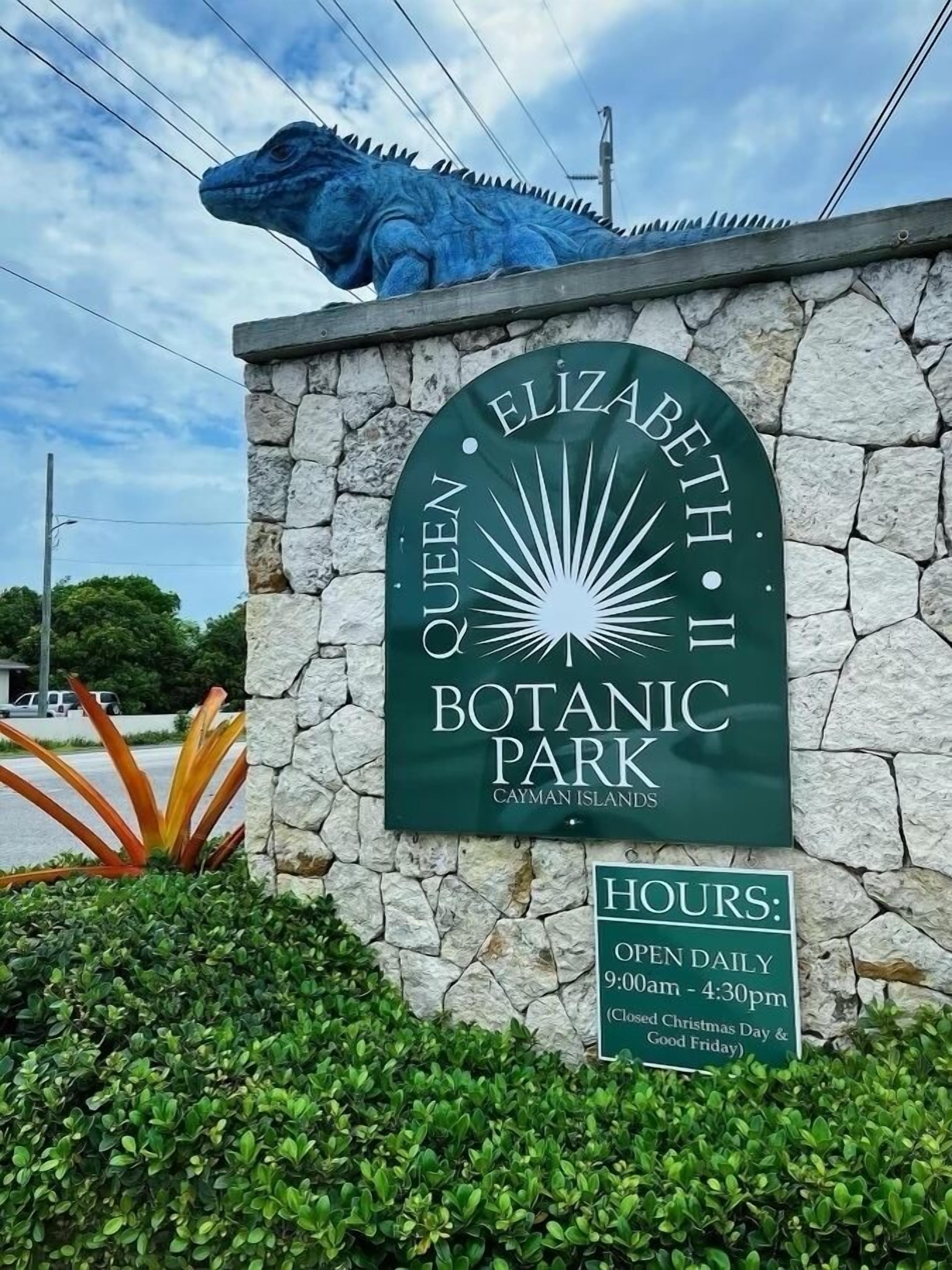 A sign for Queen Elizabeth II Botanical Park with the hours of operation listed.